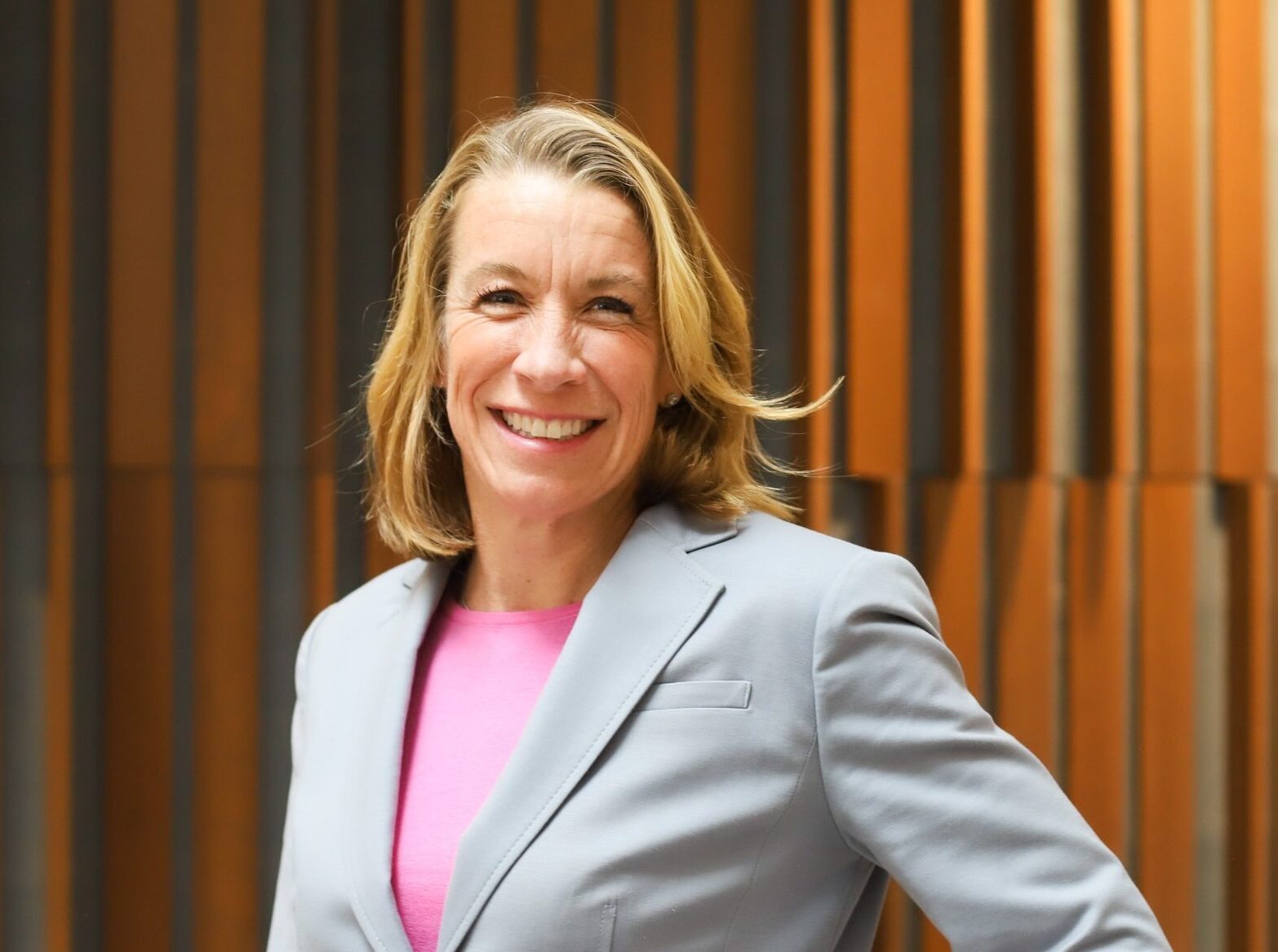 Jamie Pleune, a white woman with blonde hair wearing a pink blouse and light-grey blazer