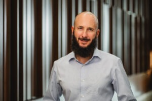 Professor Jeff Schwartz, a young white man who is bald and has a full, dark-brown beard and mustache