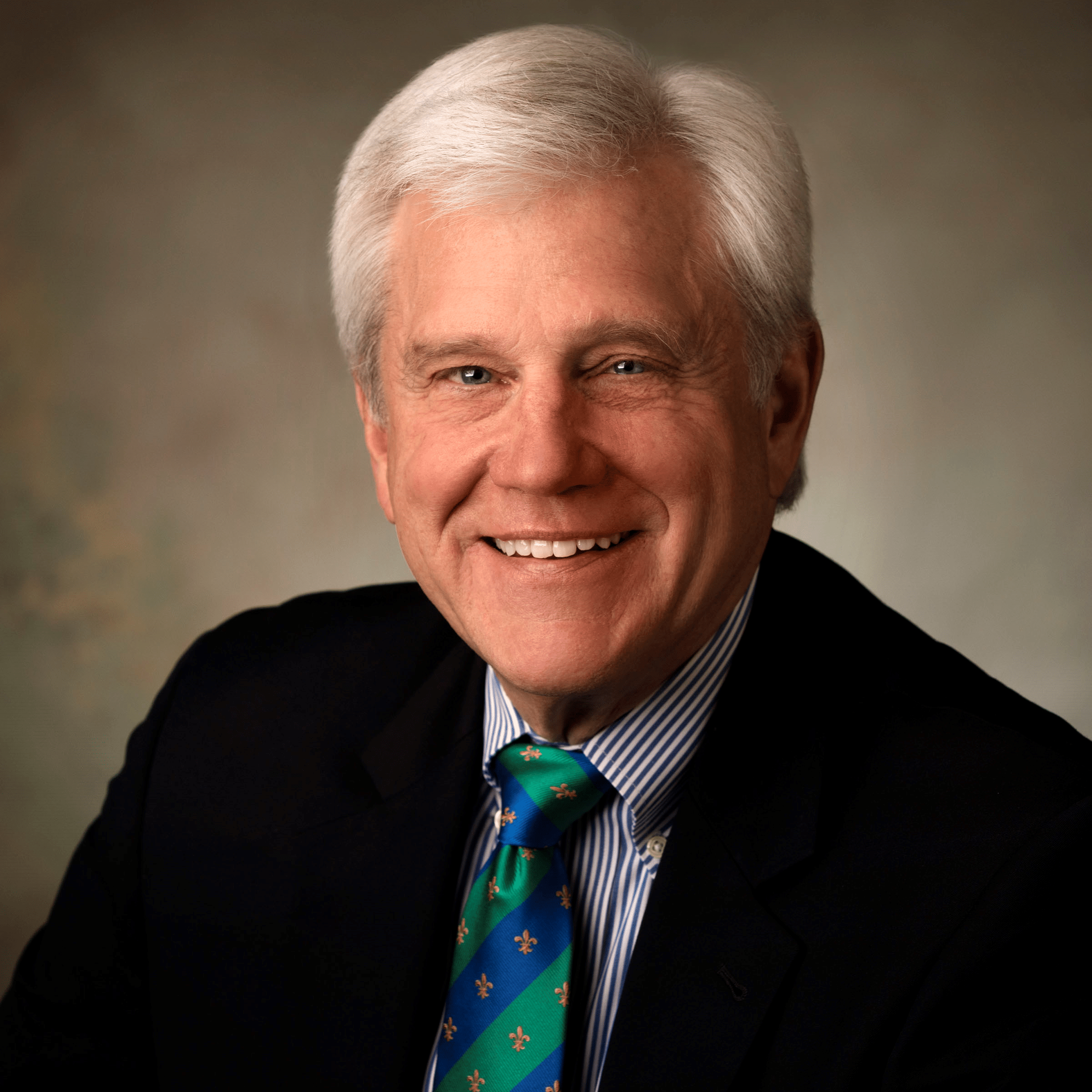 Robert Harrison, an older white man with white hair wearing a black blazer and blue- and green-striped tie