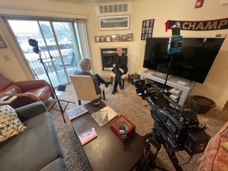 Interior of Professor Amos Guiora's Salt Lake City apartment, with a large screen door, white walls, and an interviewer talking with Amos Guiora opposite a videocamera.