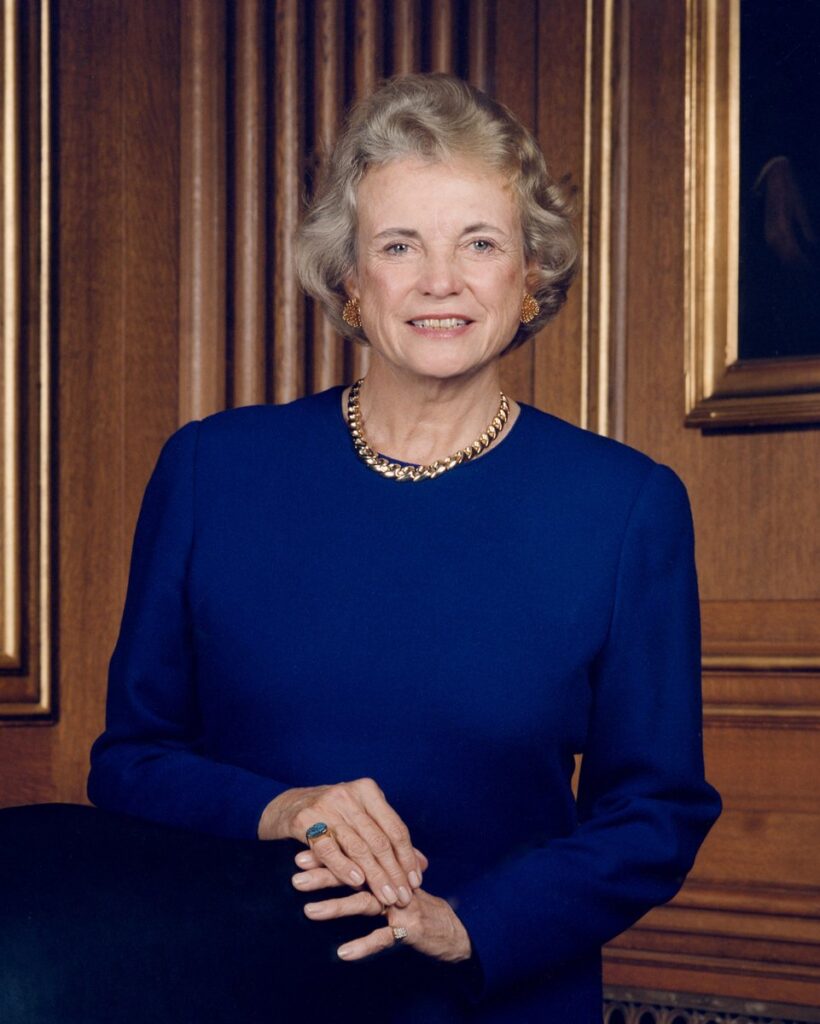 Jusitce Sandra Day O'Connor, an older white woman with short gray hair wearing a royal blue dress