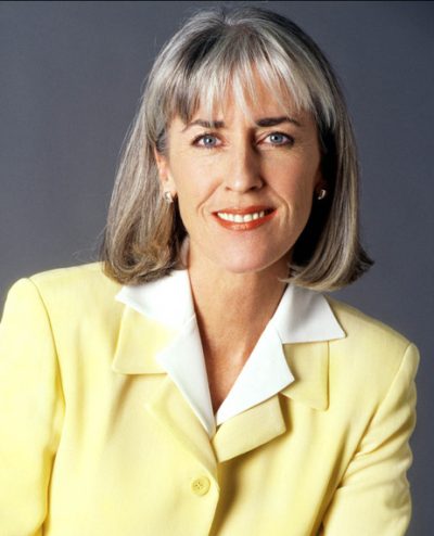 Jan Graham, an older white woman with shoulder-length grey hair wearing a white blouse and light-yellow blazer
