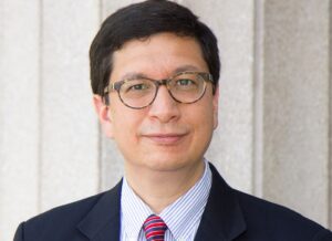 Professor Jorge Contreras, a white man with dark-brown hair wearing a navy blazer and fuchsia-striped tie