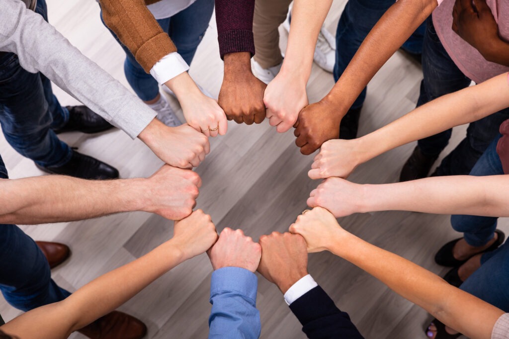 An Overhead View Of Multi-ethnic People's Hand Joining Their Fist To Form Circle