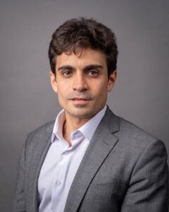 Associate professor Erick Sam, a man with dark-brown hair and dark brown eyes and olive skin wearing a charcoal suit jacket