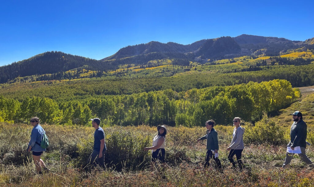 Students walk in a line amid the golden fields and mountain landscape of Northern Utah